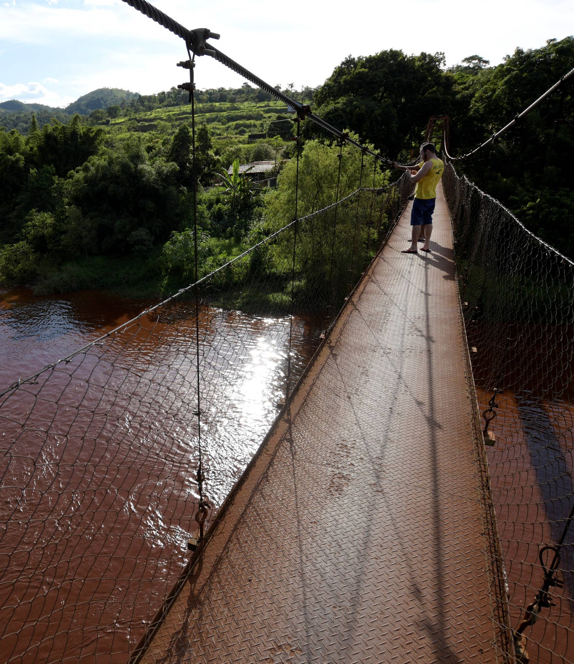 Residents stand on a bridge over mud-filled Paraopeba river, after a tailings dam owned by Brazilian mining company Vale SA collapsed, in Mario Campos near Brumadinho