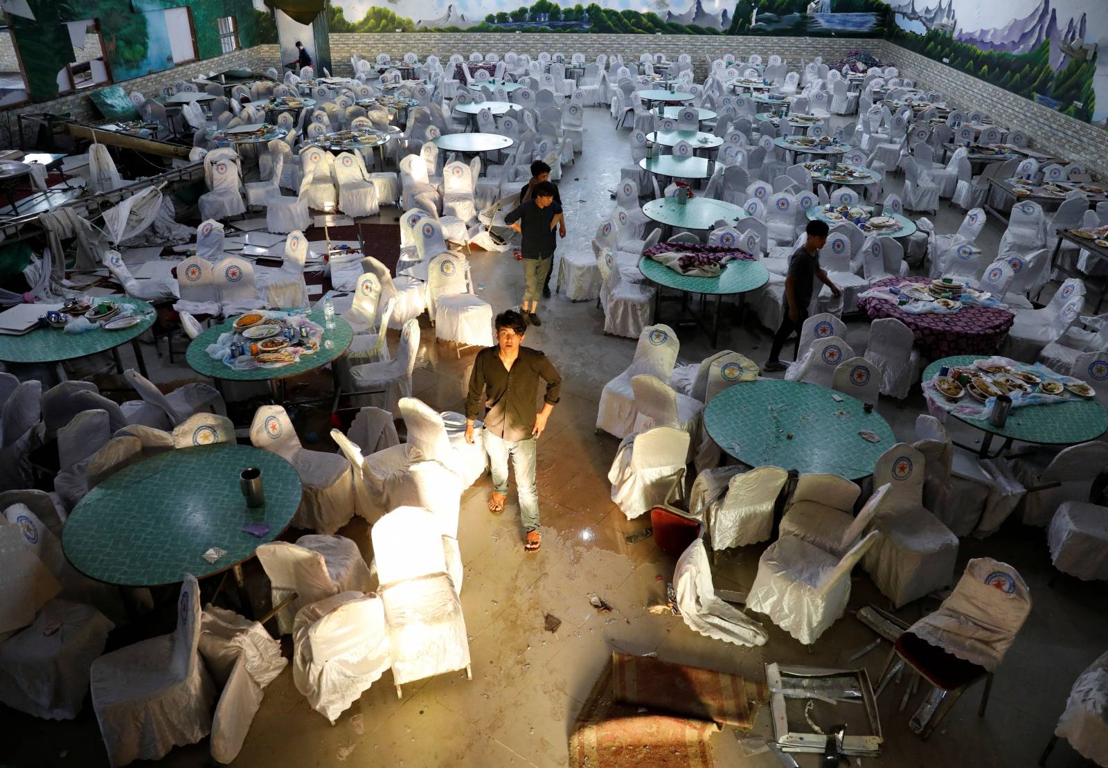 Workers inspect a damaged wedding hall after a blast in Kabul, Afghanistan