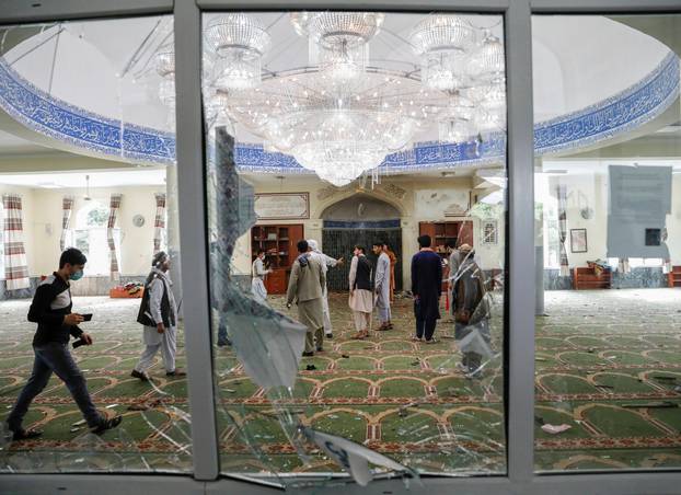 Men inspect the site of a blast inside a mosque in Kabul, Afghanistan
