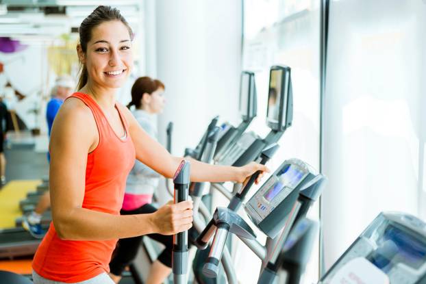 Young fit woman using an elliptic trainer