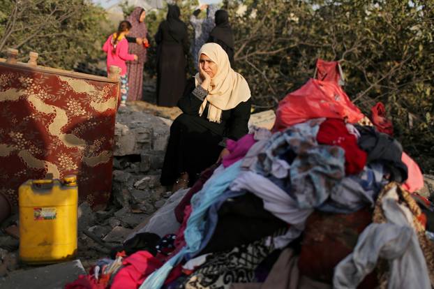 Palestinian woman reacts as she sits at the remains of a house destroyed in an Israeli air strike in the southern Gaza Strip