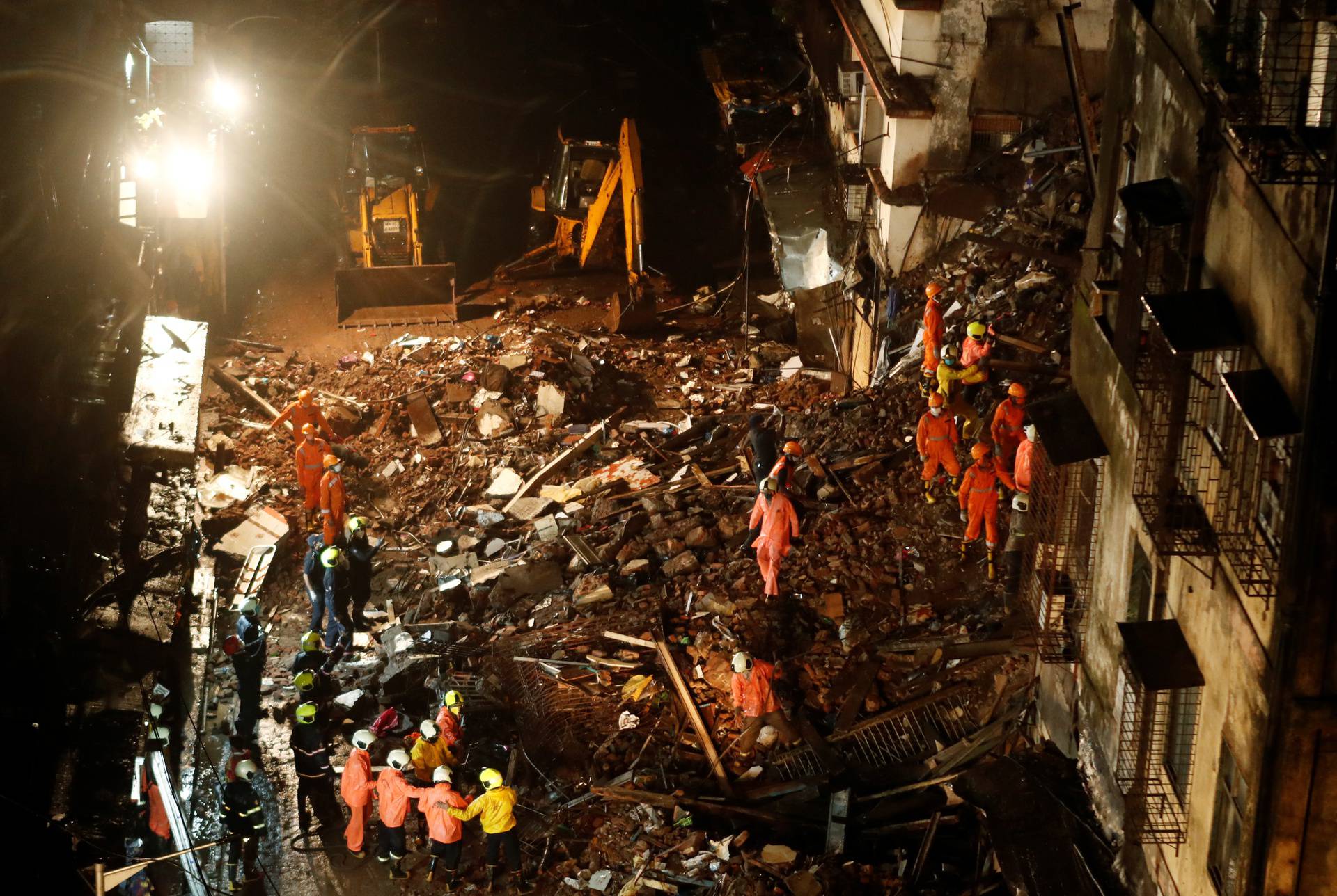 National Disaster Response Force (NDRF) and fire brigade personnel look for survivors trapped in the debris after part of a residential building collapsed following heavy rains in Mumbai