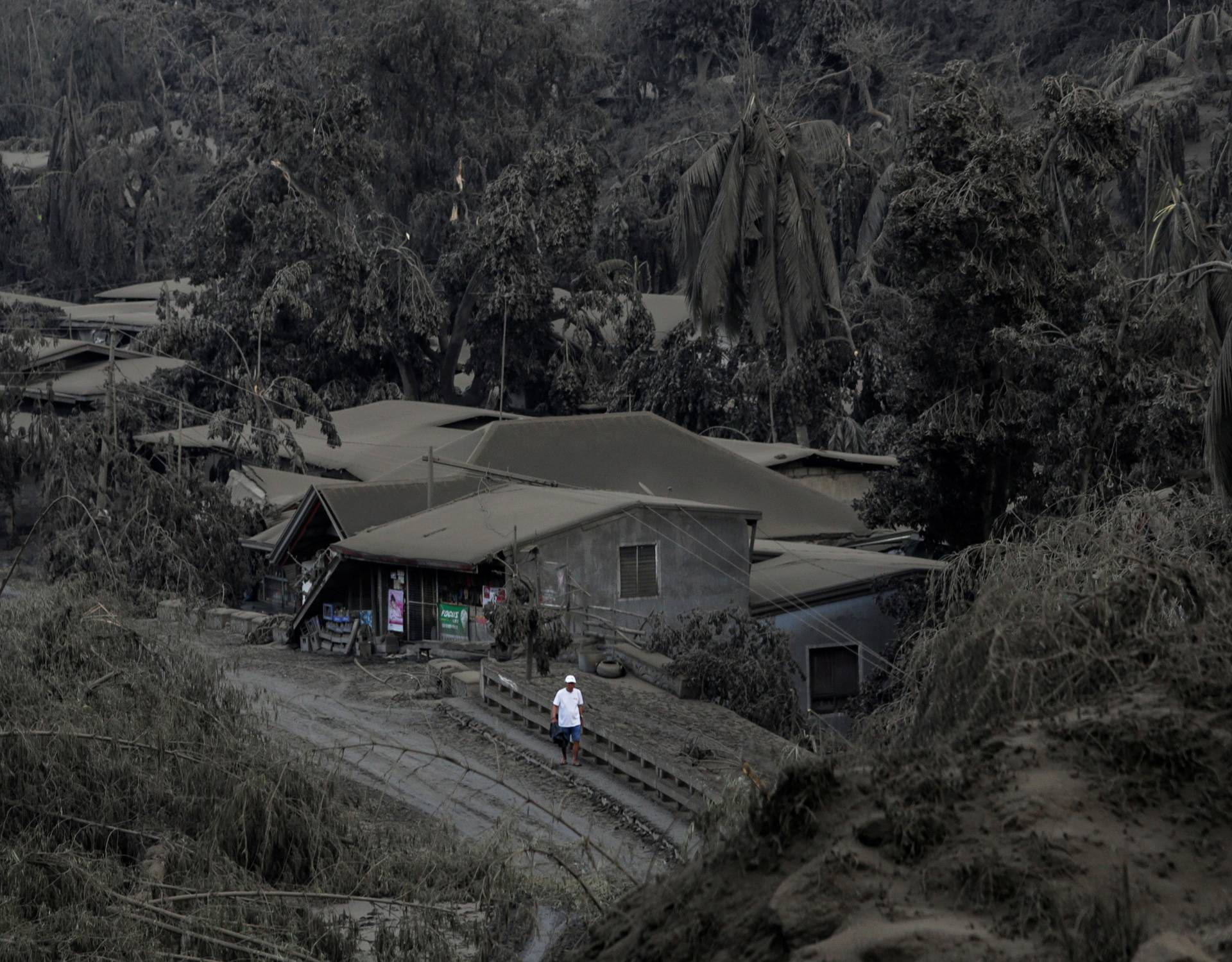 A man walks on a road covered with ashes from the erupting Taal Volcano in Talisay