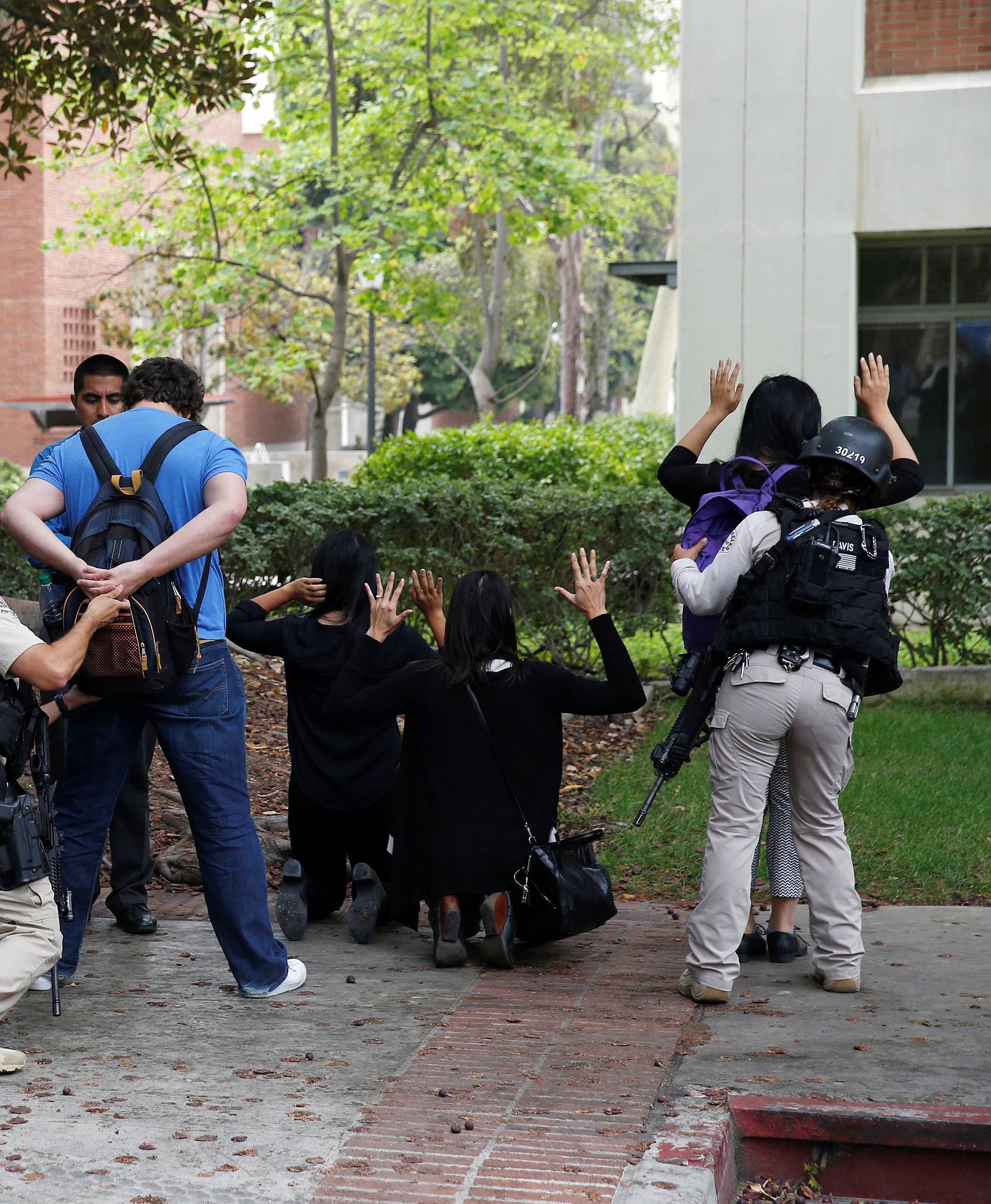 Police officers conduct a search on people at the UCLA campus after it was placed on lockdown following reports of a shooter that left 2 people dead in Los Angeles, California