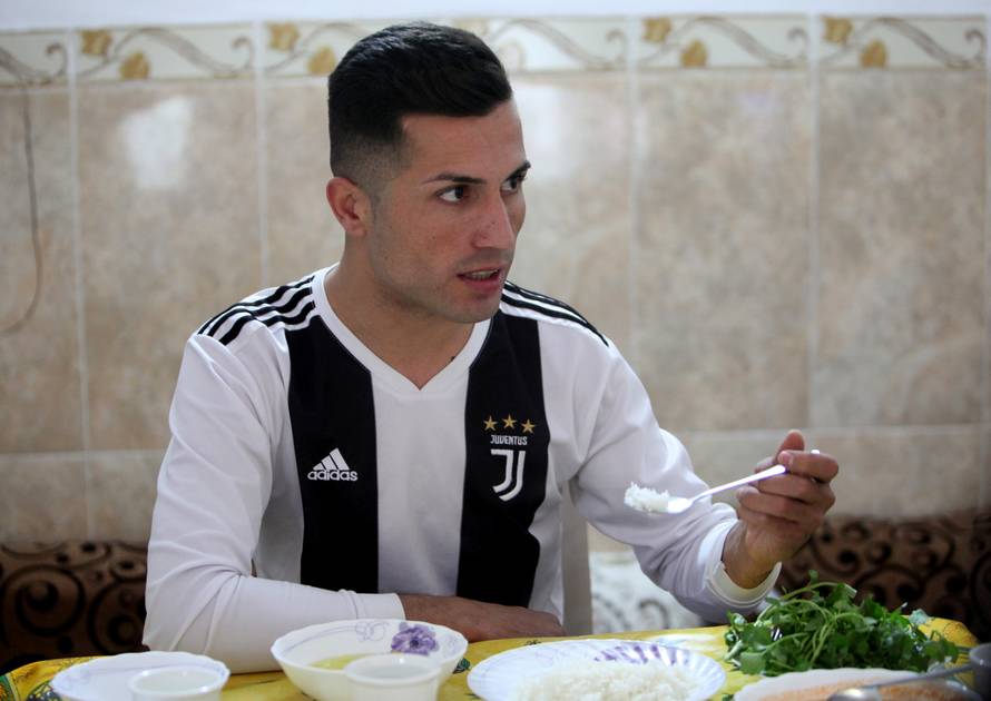 Biwar Abdullah, 25, an Iraqi Kurdish local footballer, who looks like the football player Cristiano Ronaldo, eats at his home in the district of Soran, northeast of Erbil