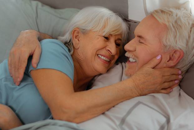 Close-up of husband and wife hugging and lying in bed.