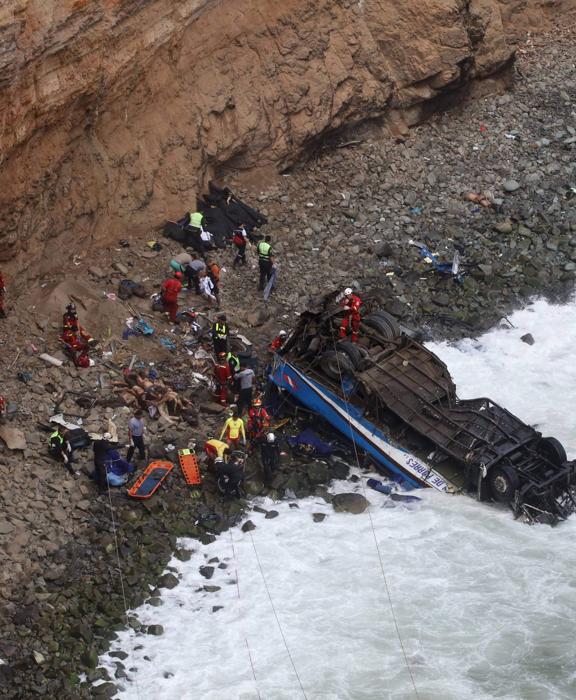 Rescue workers  and police work at the scene after a bus crashed with a truck and careened off a cliff along a sharply curving highway north of Lima