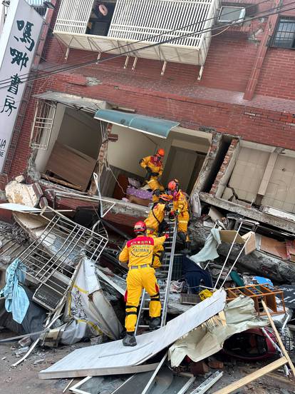 Firefighters work at the site where a building collapsed following the earthquake, in Hualien