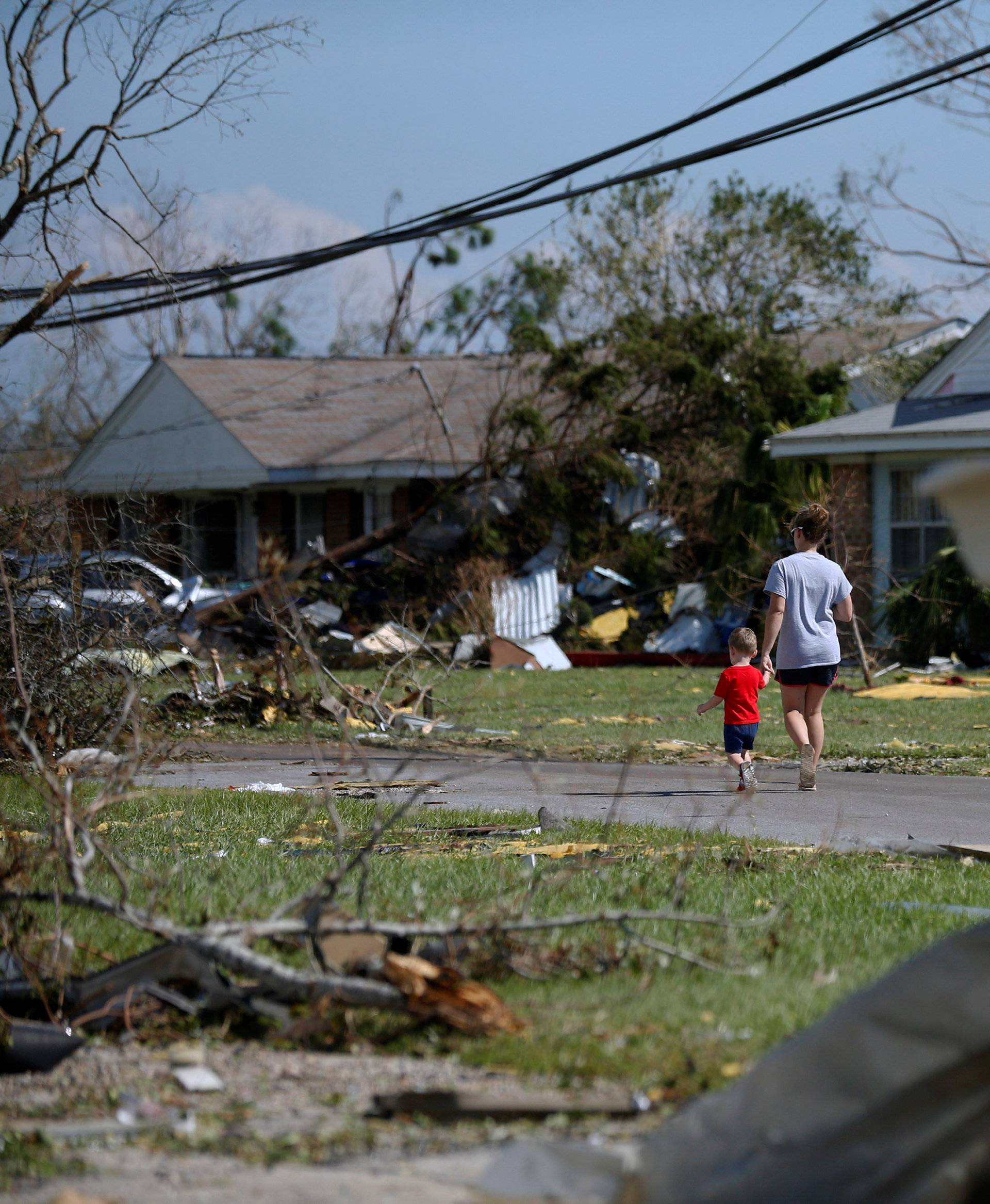 A mother and her son walk down a street damaged by Hurricane Michael in Callaway