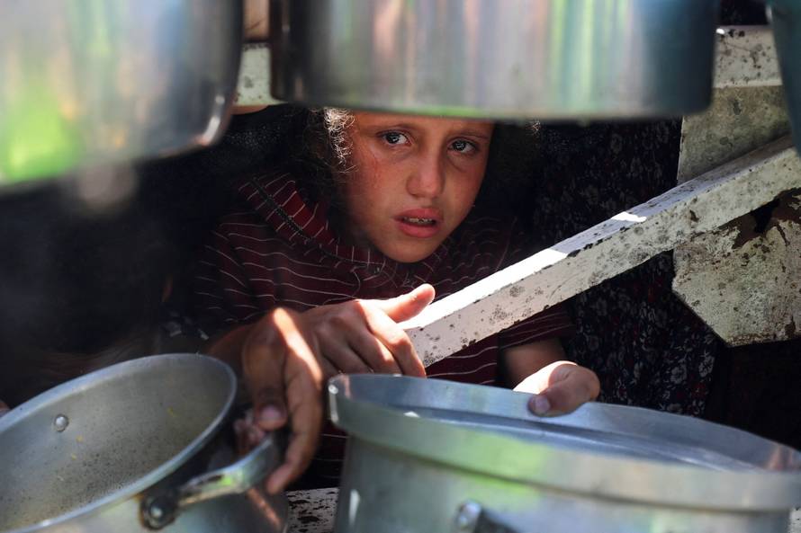Palestinians wait to receive food from a charity kitchen, in Gaza City