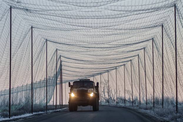 Military truck moves along a road covered with an anti-drone net in Kharkiv region