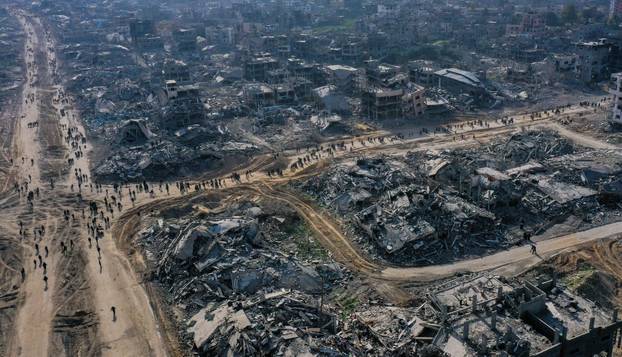 Displaced Palestinians walk past the rubble as they attempt to return to their homes, in the northern Gaza Strip