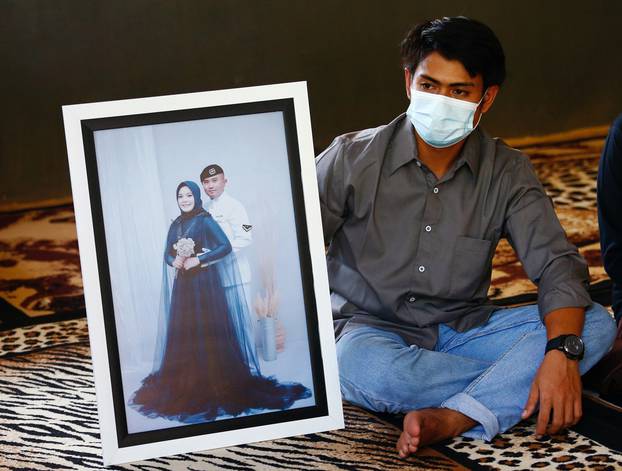 Imam Yoga, 26-year-old brother-in-law of Pandu Yudha Kusuma, 23, one of the crew members of the sunken KRI Nanggala-402 submarine, shows a photograph during an interview at his parents
