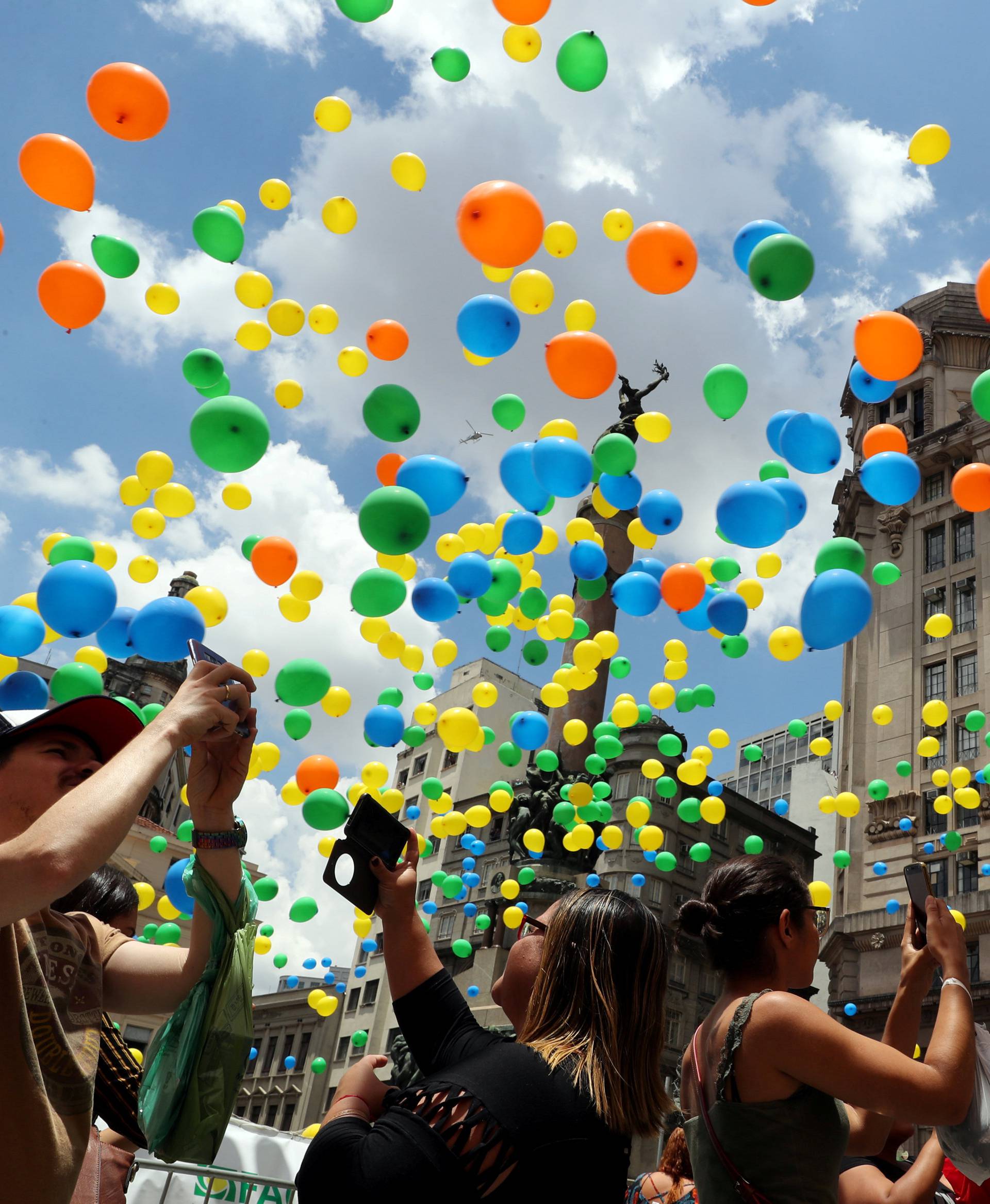 People take pictures of balloons being released in the sky of downtown Sao Paulo as part of year-end celebrations