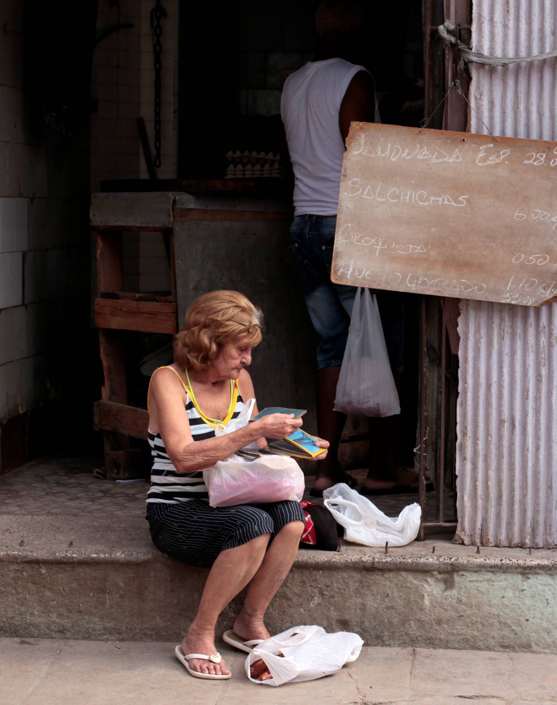 Woman sits along a street in Havana, Cuba