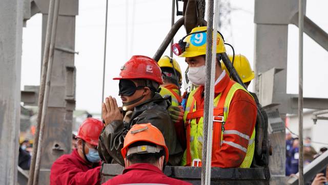Rescue workers help a miner at the Hushan gold mine after explosion in Qixia, Shandong