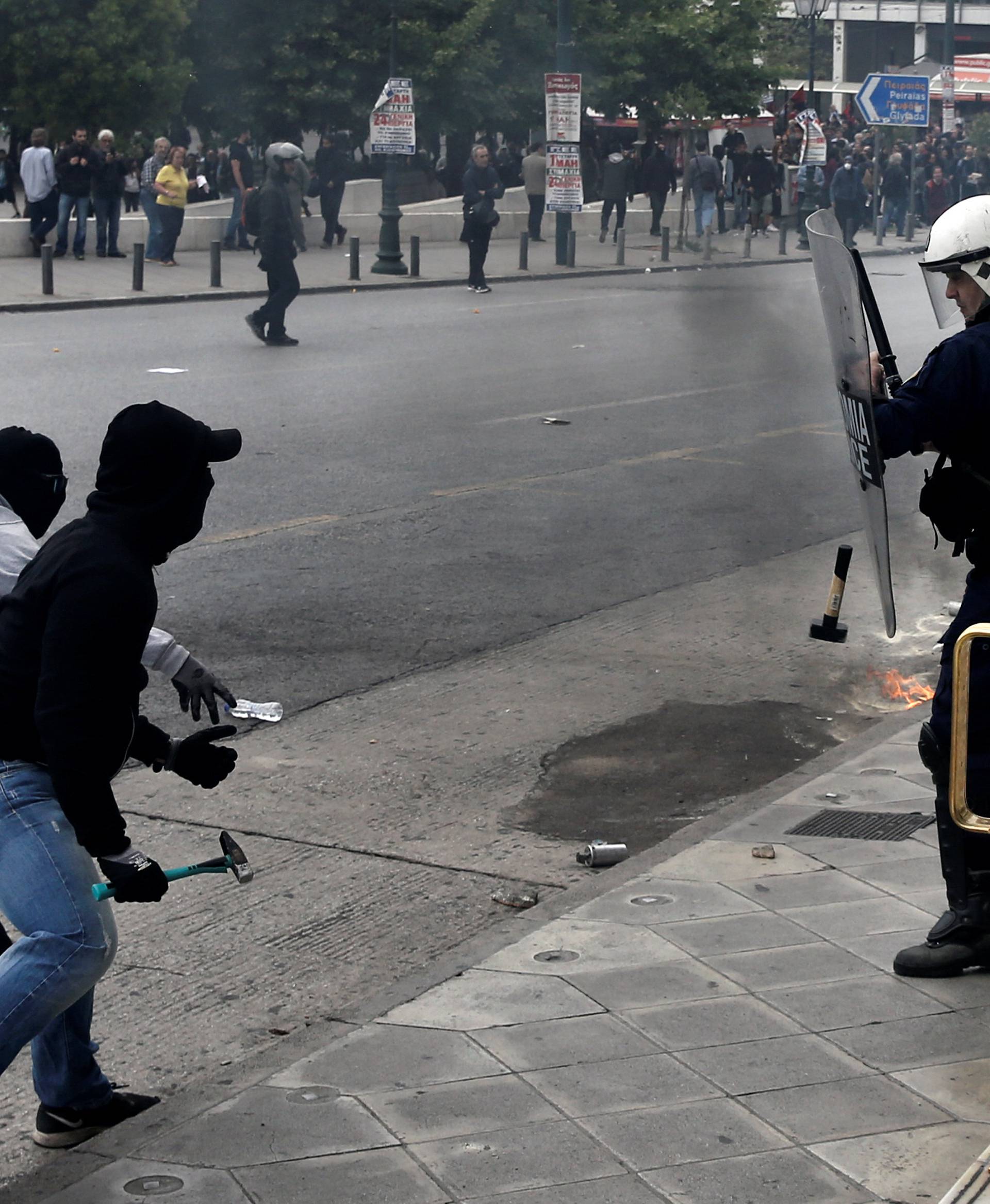 A demonstrator throws a hammer at riot police during a demonstration marking a 24-hour general strike against the latest round of austerity in Athens