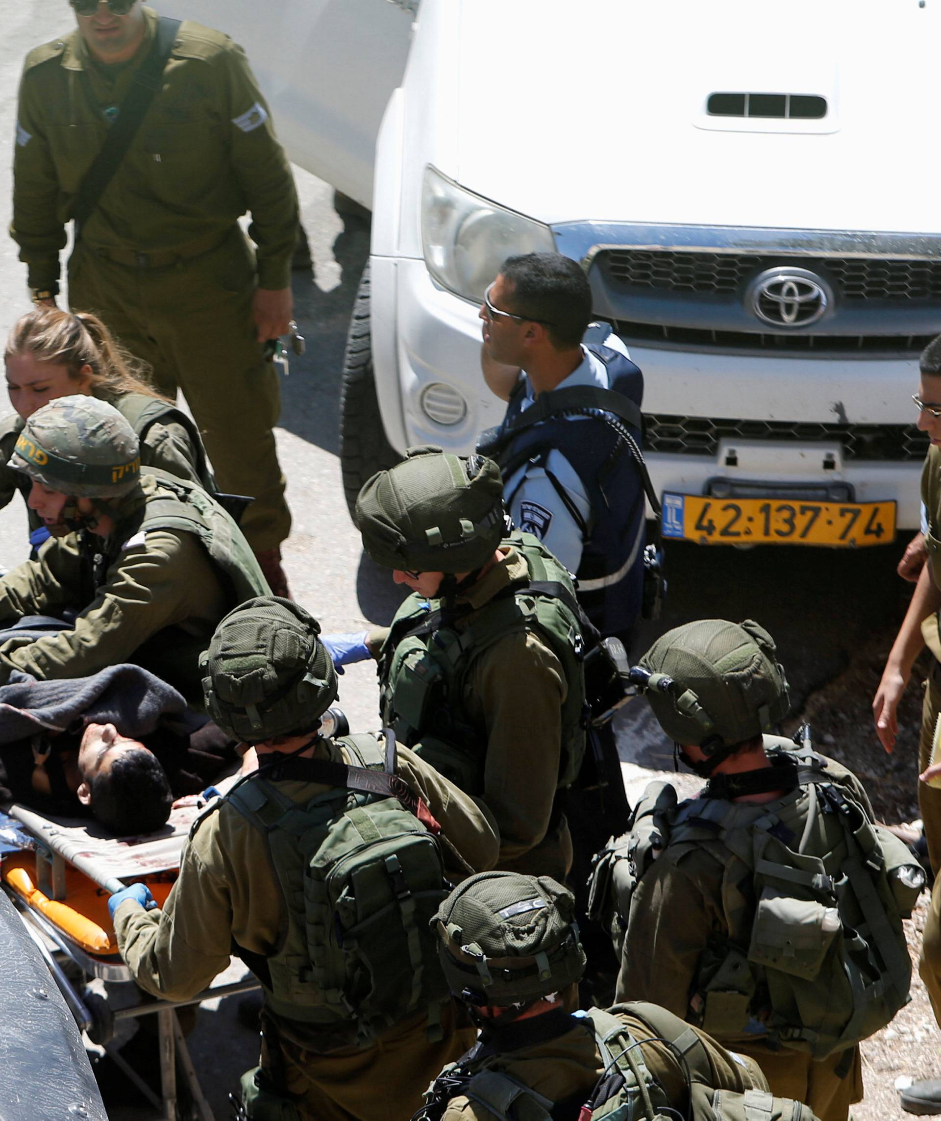 Israeli forces carry on a stretcher a Palestinian assailant after he was shot by Israeli troops at the scene of a stabbing attack in the West Bank city of Hebron