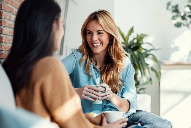 Shot,Of,Two,Smiling,Young,Women,Talking,While,Drinking,Coffee