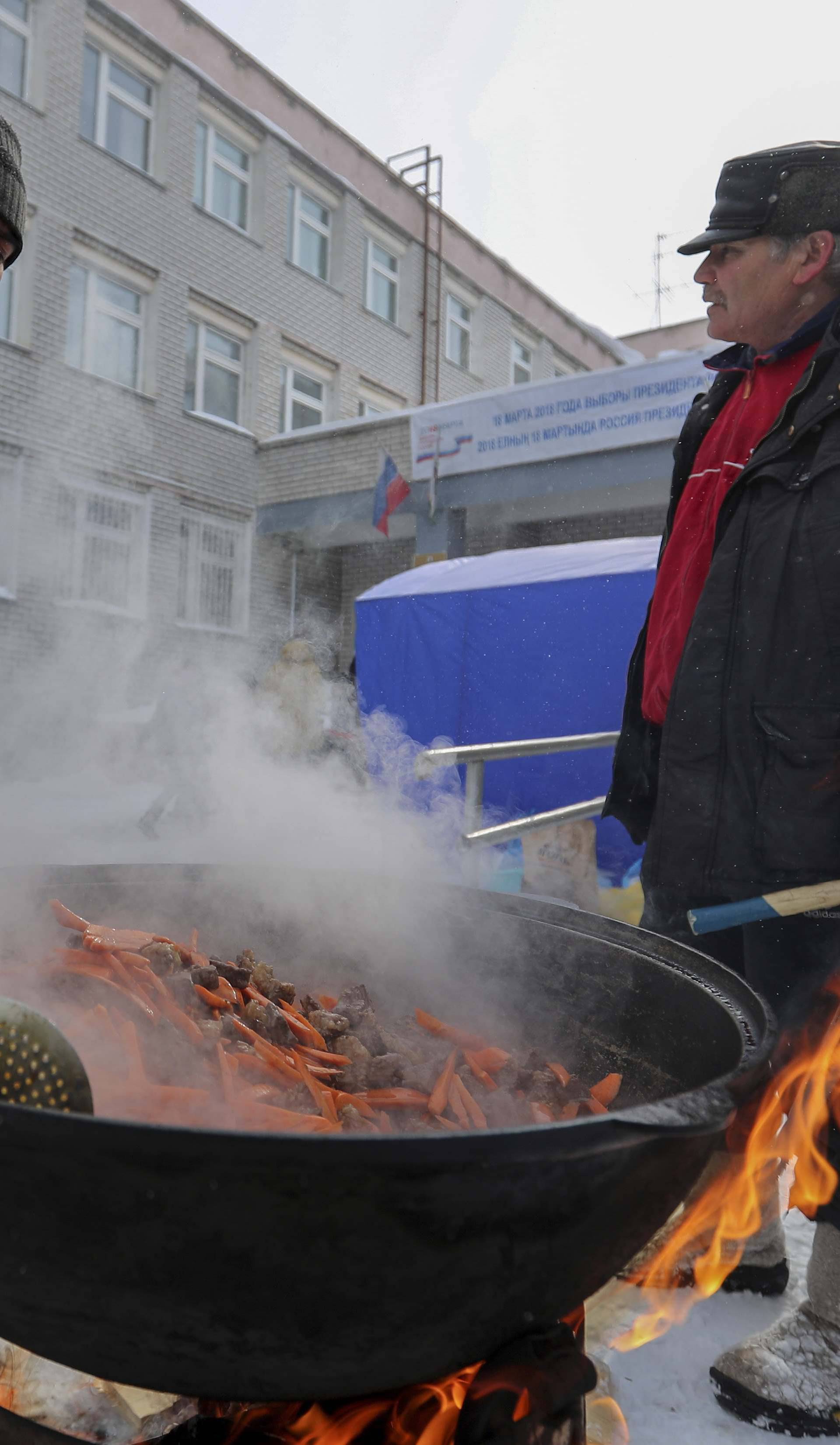People cook a traditional meal near a polling station during the presidential election in Kazan