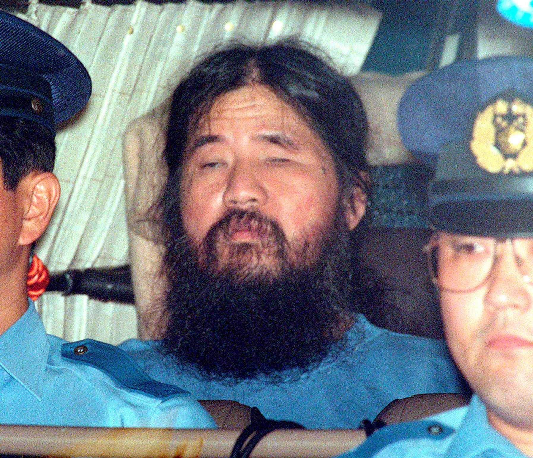 Japanese doomsday cult leader Shoko Asahara sits in a police van following an interrogation in Tokyo