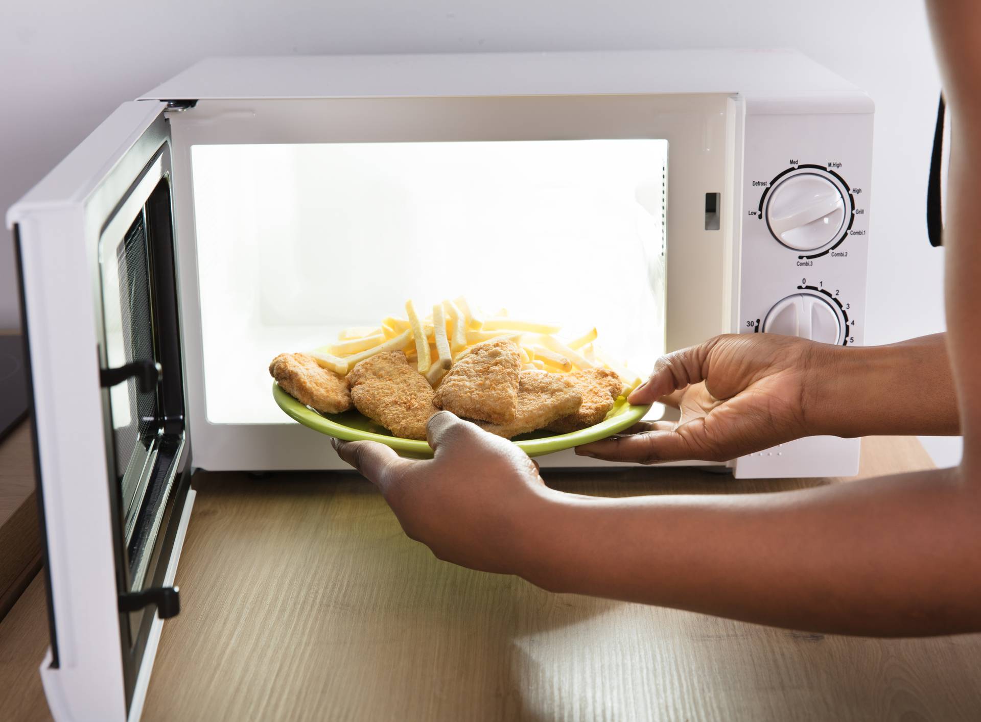 Person Heating Fried Food In Microwave Oven