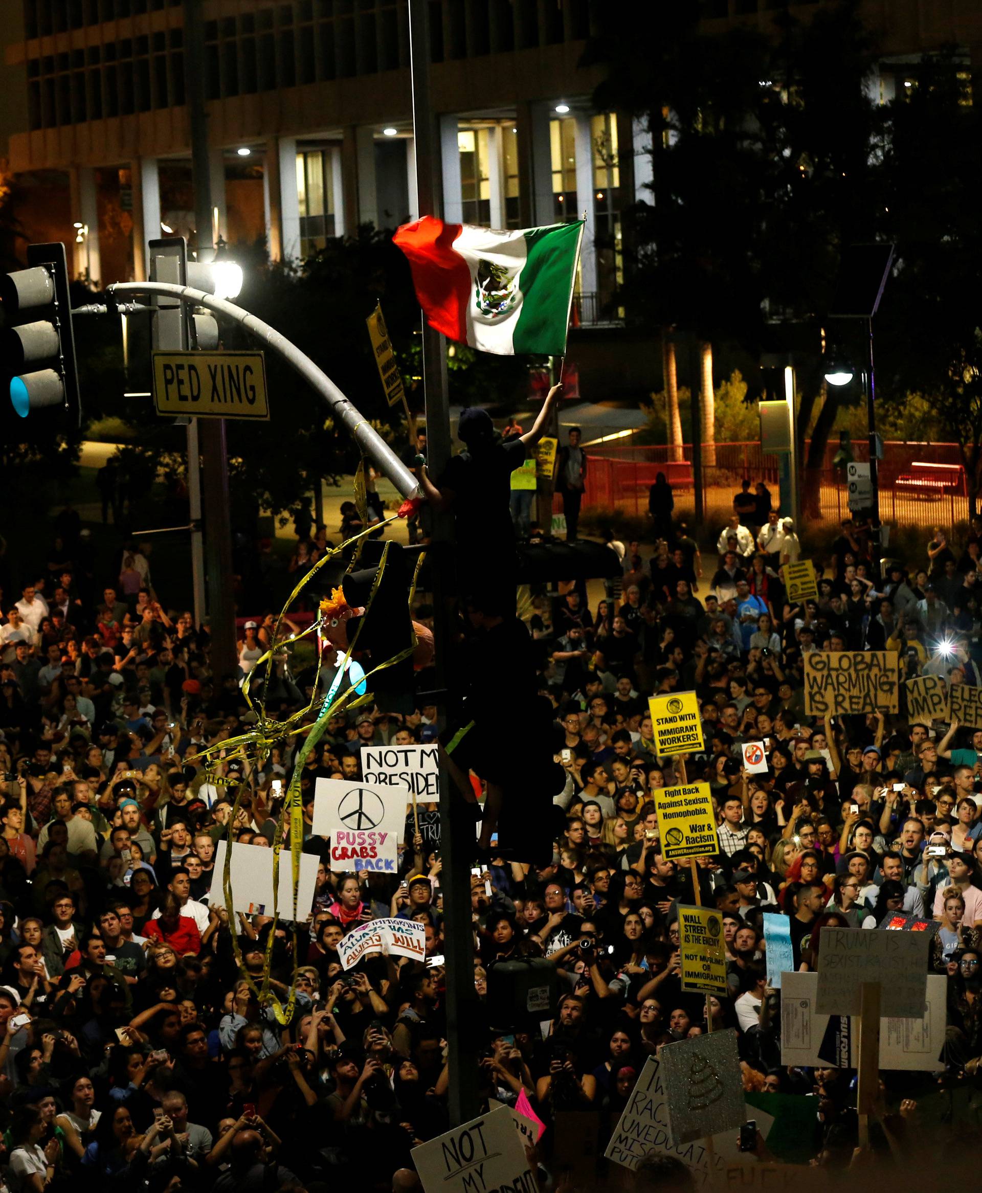 A protester waves a Mexican flag as others gather to protest to the election of Republican Donald Trump as the president of the United States outside City Hall in Los Angeles