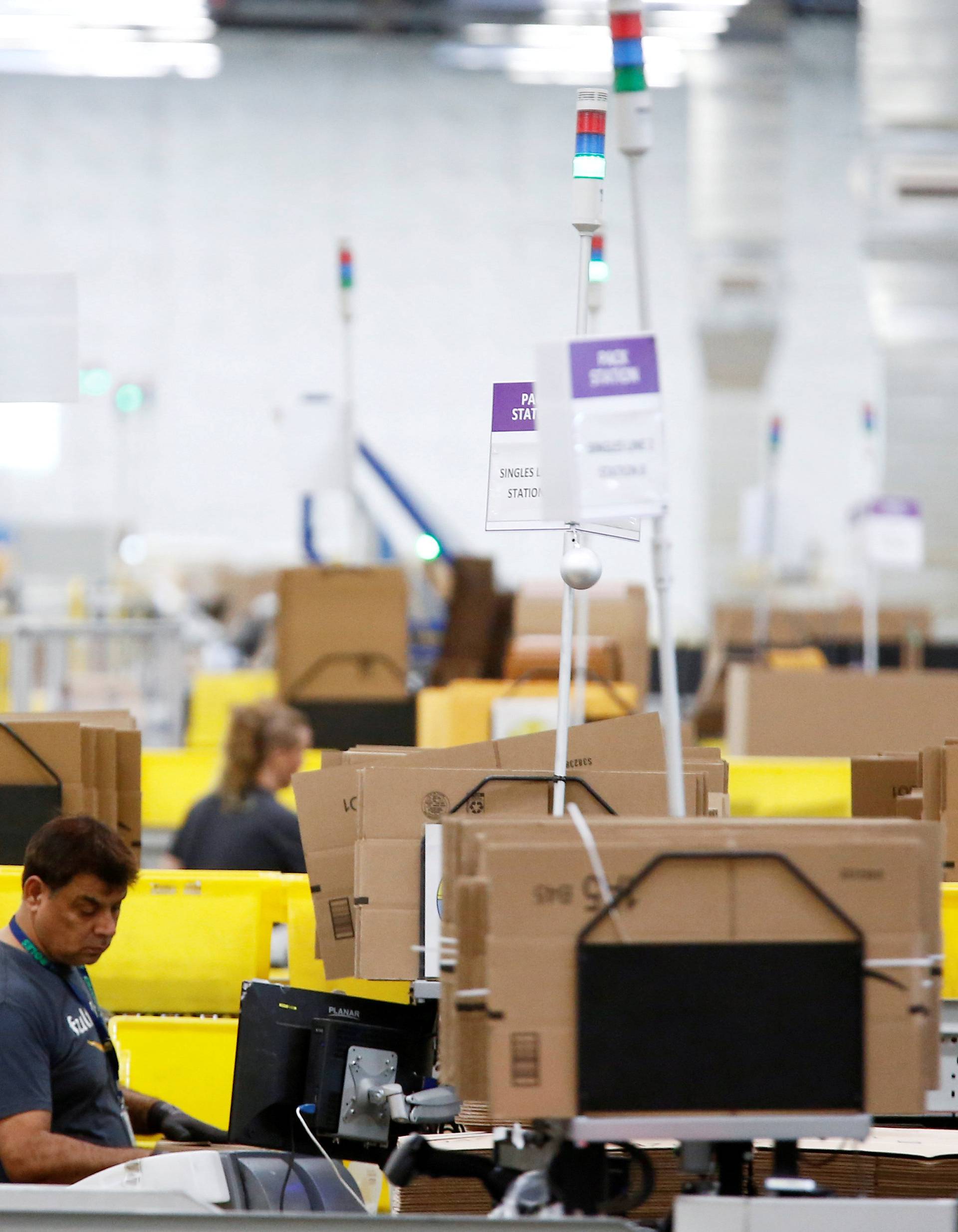 FILE PHOTO: Employees work at packing stations on the main floor at the Amazon fulfillment center in Kent
