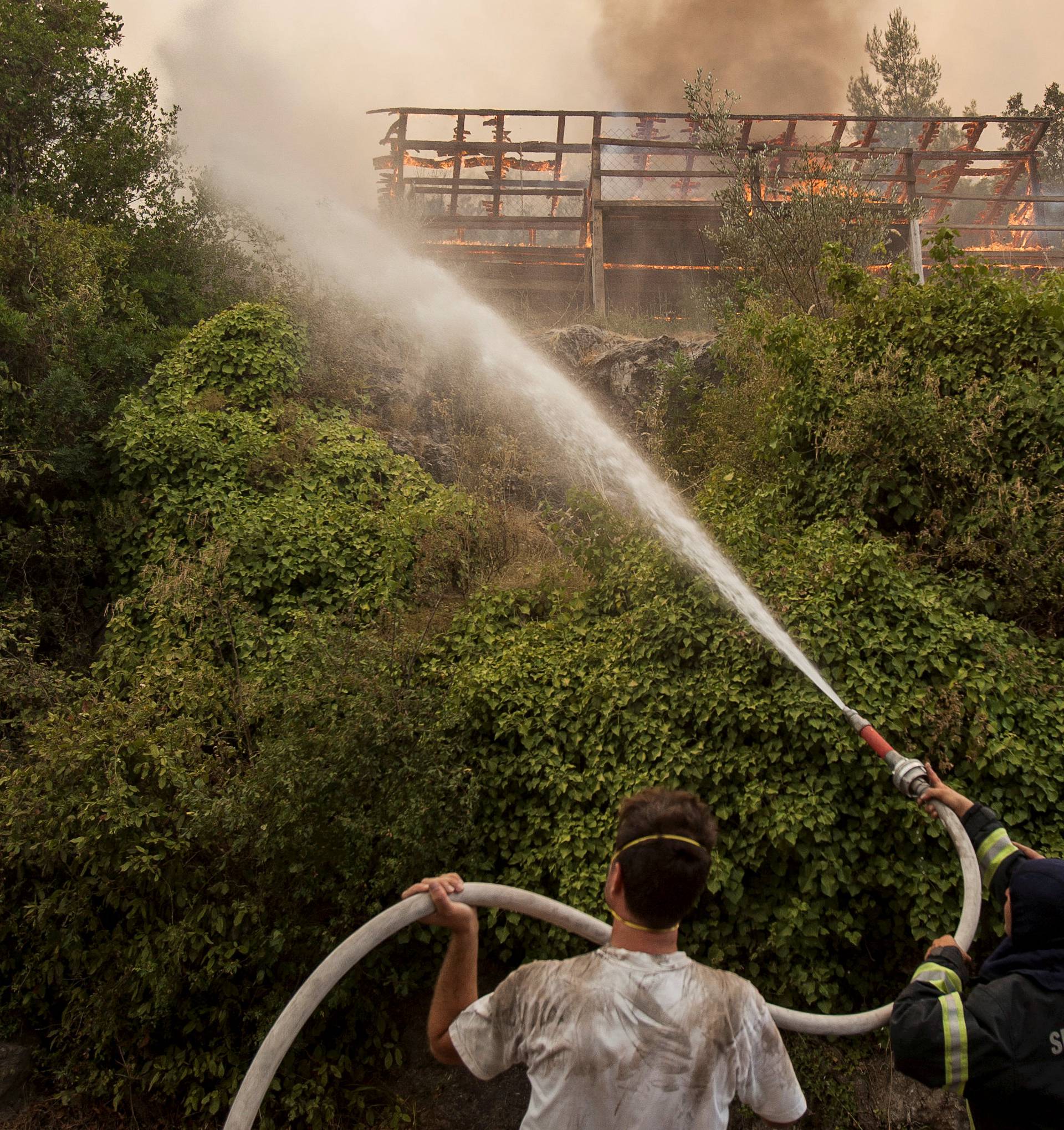 Firefighters try to control flames around a burning cabin during a forest fire at Lustica peninsula near Tivat