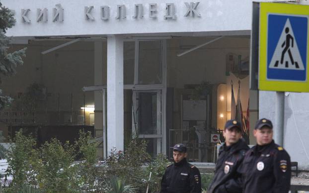 Russian policemen gather outside the damaged building of a college following a recent attack in Kerch