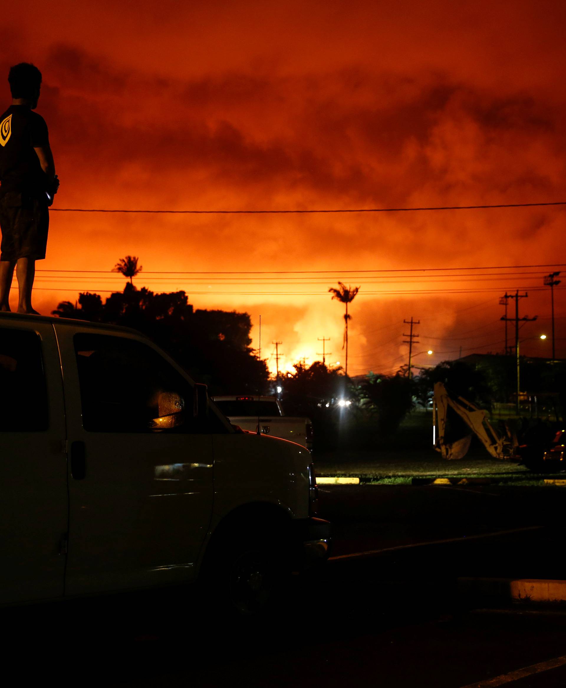 A man watches as lava lights up the sky above Pahoa