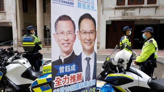 Police officers stand guard next to o a campaign banner outside a polling station during the Legislative Council election in Hong Kong