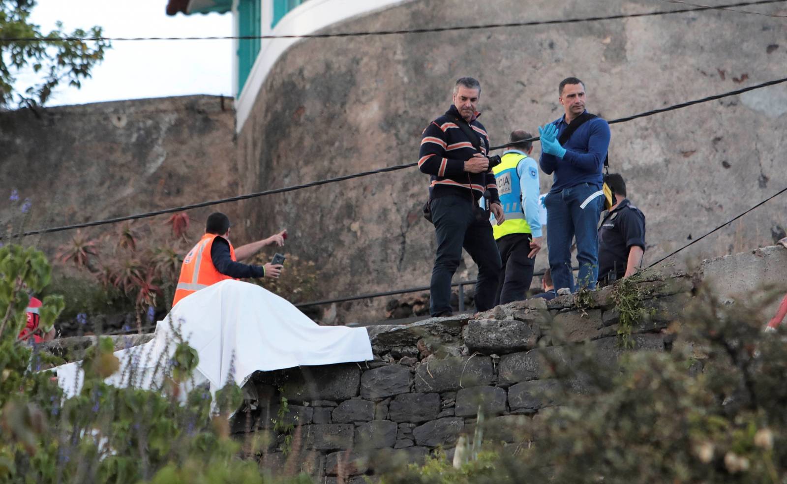 Rescue workers stand at the scene of a bus accident in Canico