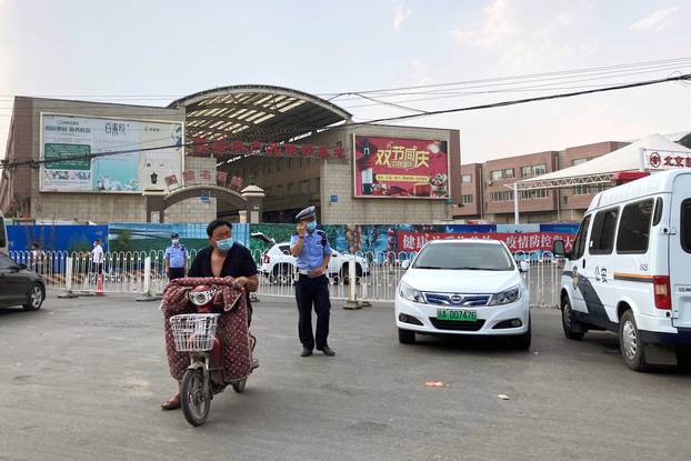 Police officers wearing face masks are seen outside the Xinfadi wholesale market, which has been closed for business after new coronavirus infections were detected, in Beijing