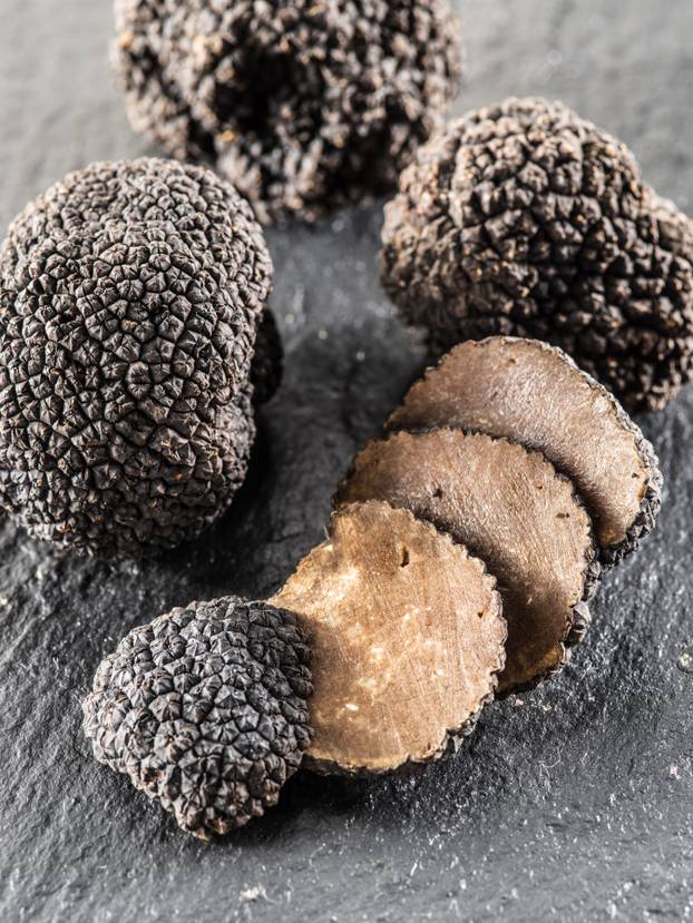 Black truffles and truffle slices on the graphite board.