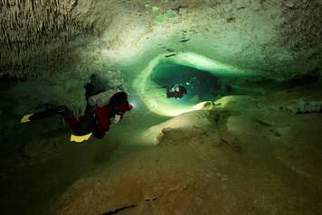 Scuba divers tour an authorized area of Sac Aktun underwater cave system as part of the Gran Acuifero Maya Project near Tulum