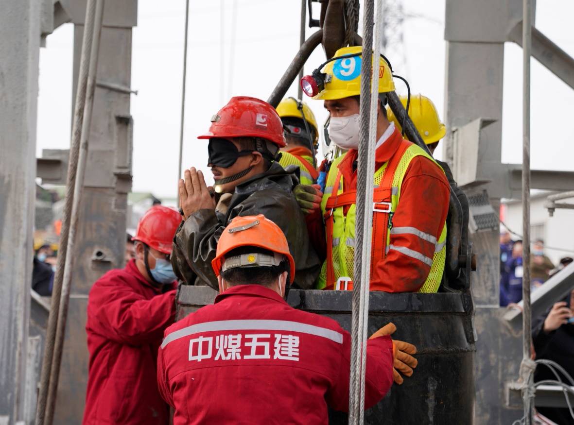 Rescue workers help a miner at the Hushan gold mine after explosion in Qixia, Shandong