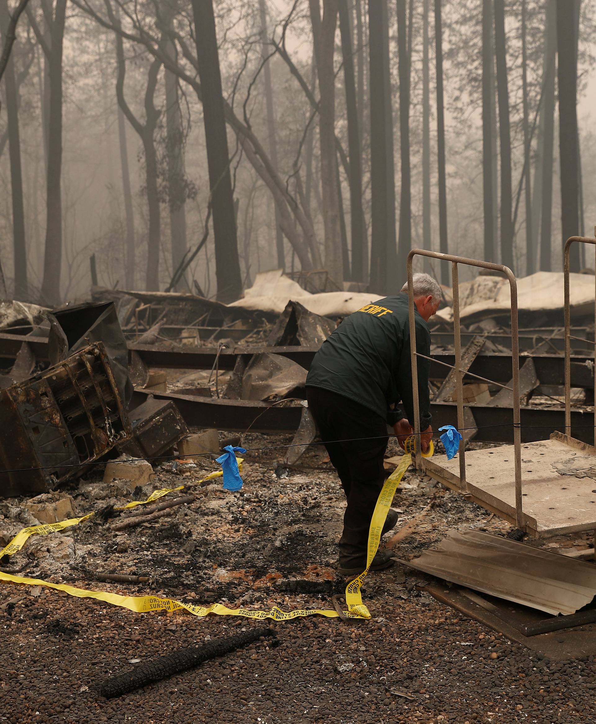 FILE PHOTO: A Butte County Sheriff deputy places yellow tape at the scene where human remains were found during the Camp fire in Paradise