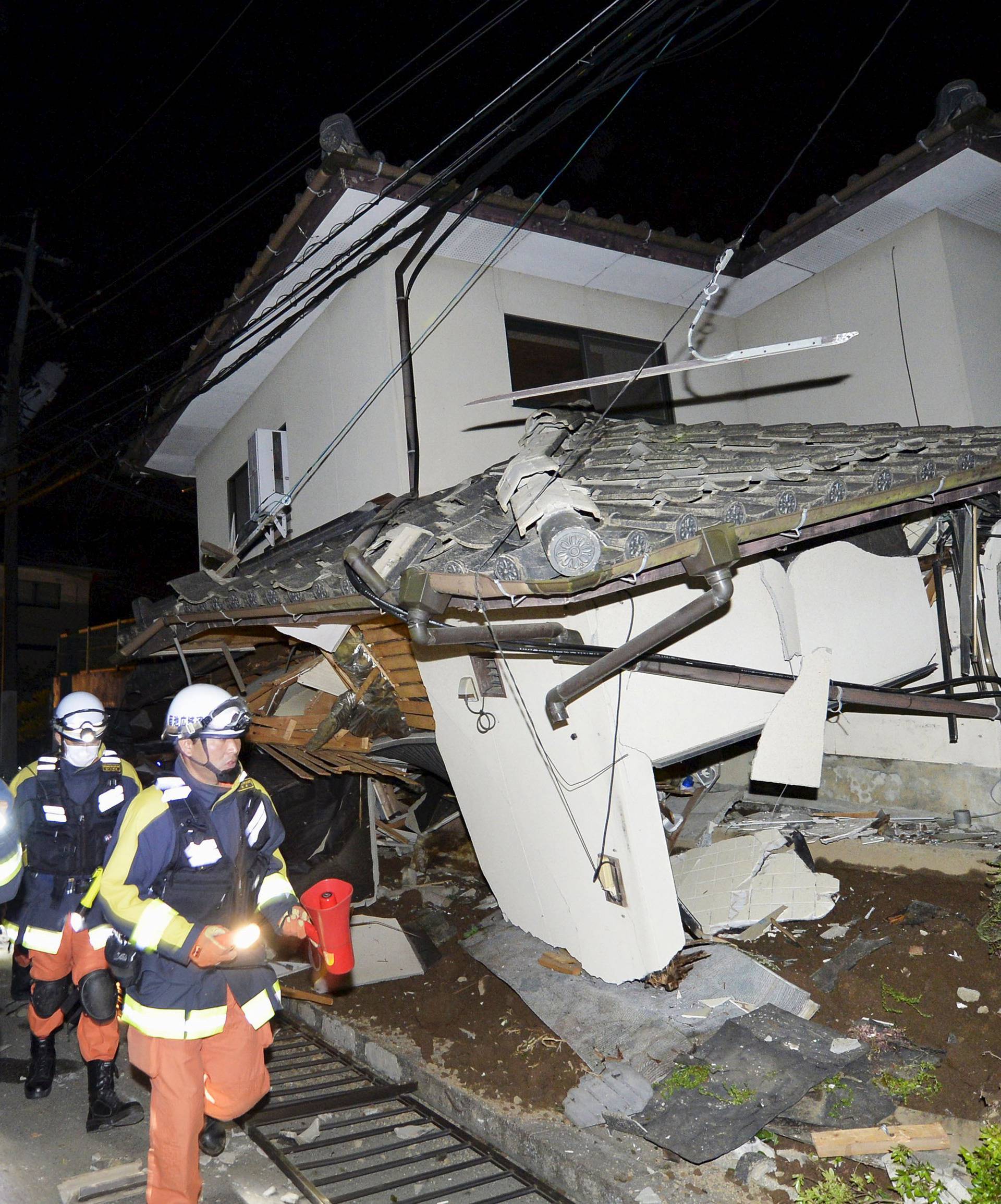 Firefighters check collapsed house after an earthquake in Mashiki town, Kumamoto prefecture, southern Japan