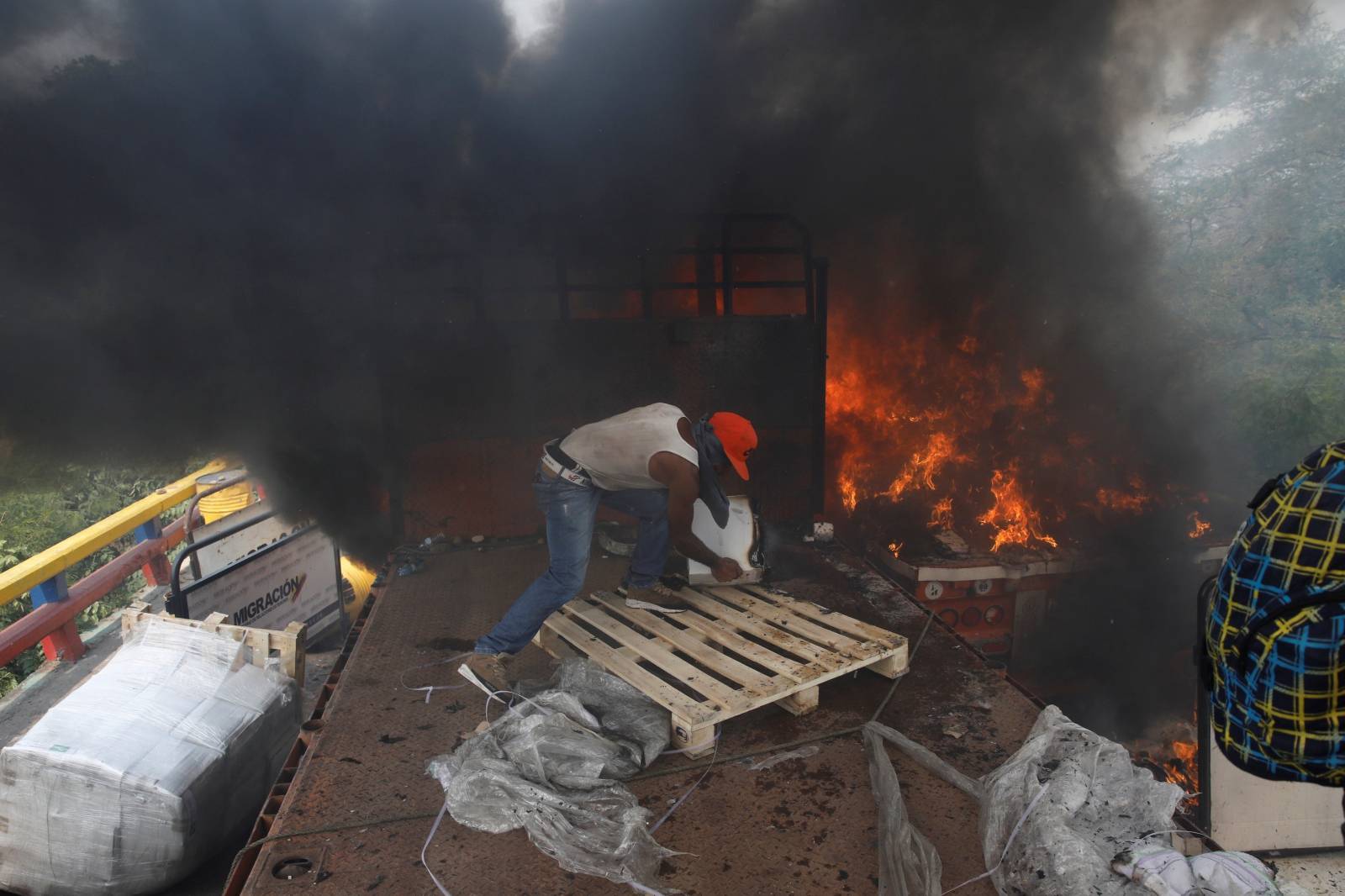 Opposition supporters unload humanitarian aid from a truck that was sent on fire in Cucuta