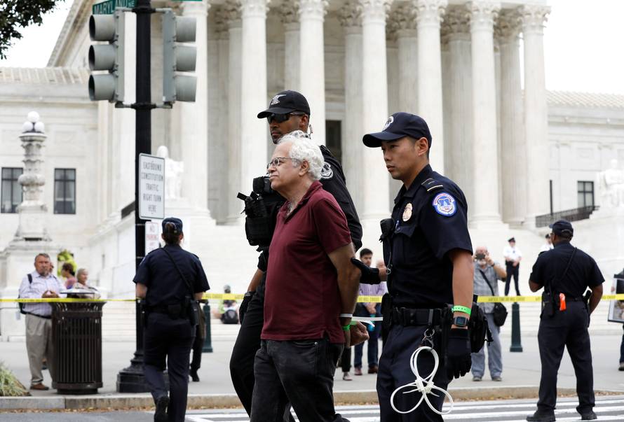 Protestor is arrested for blocking street in front of U.S. Supreme Court while demostrating against confirmation of Supreme Court nominee Kavanaugh on Capitol Hill in Washington