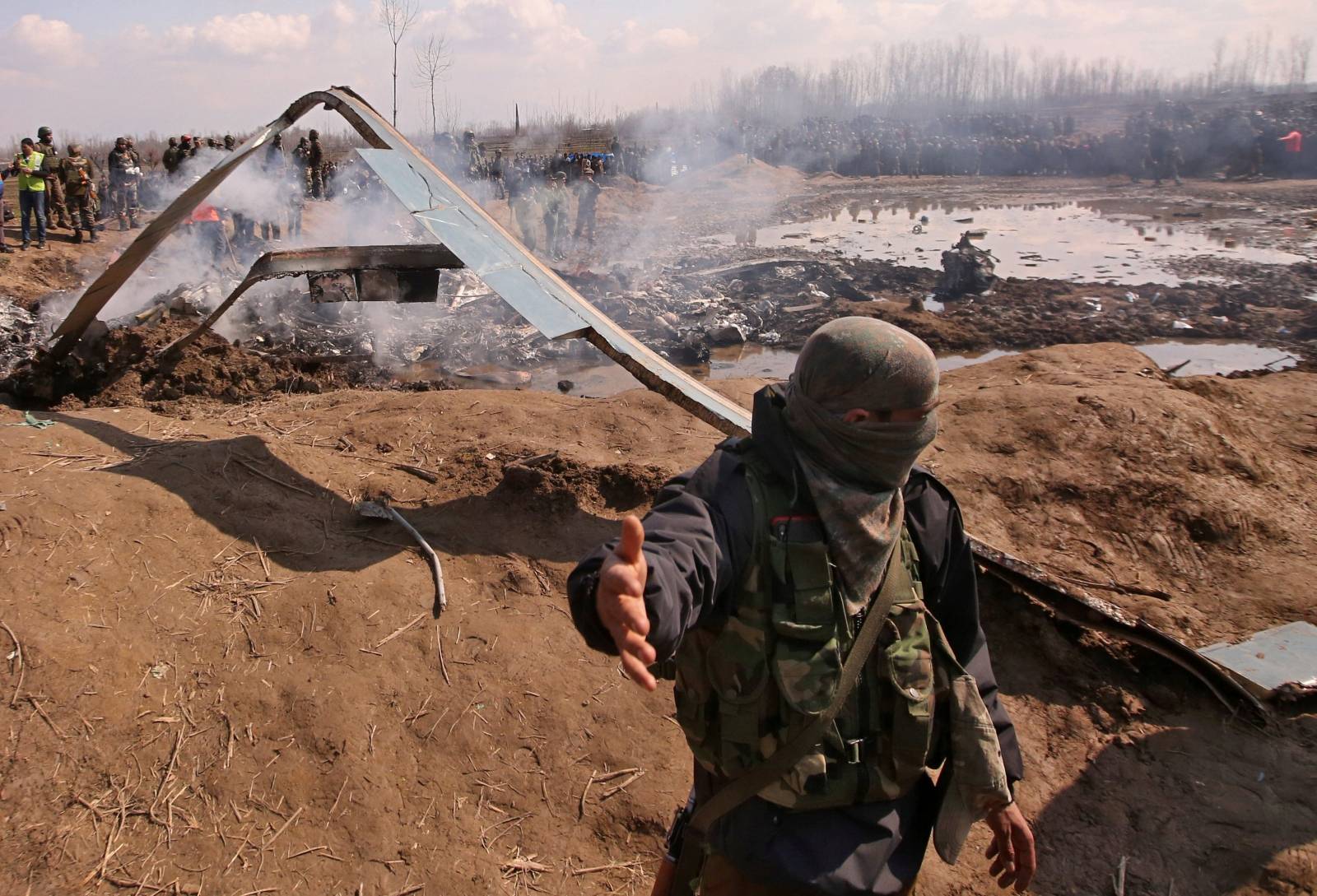 An Indian soldier gestures next to the wreckage of Indian Air Force's helicopter after it crashed in Budgam