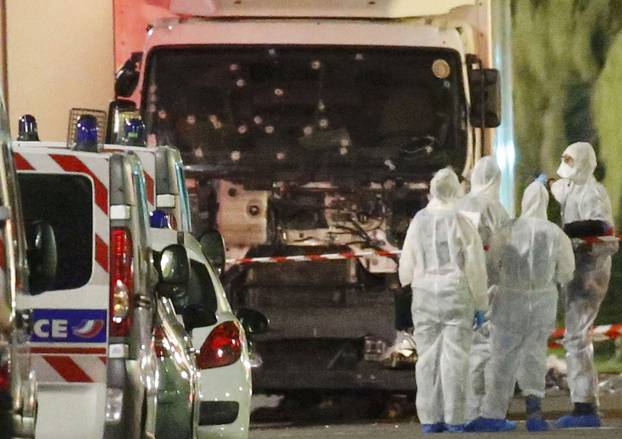 French police forces and forensic officers stand next to a truck that ran into a crowd celebrating the Bastille Day national holiday on the Promenade des Anglais killing at least 60 people in Nice