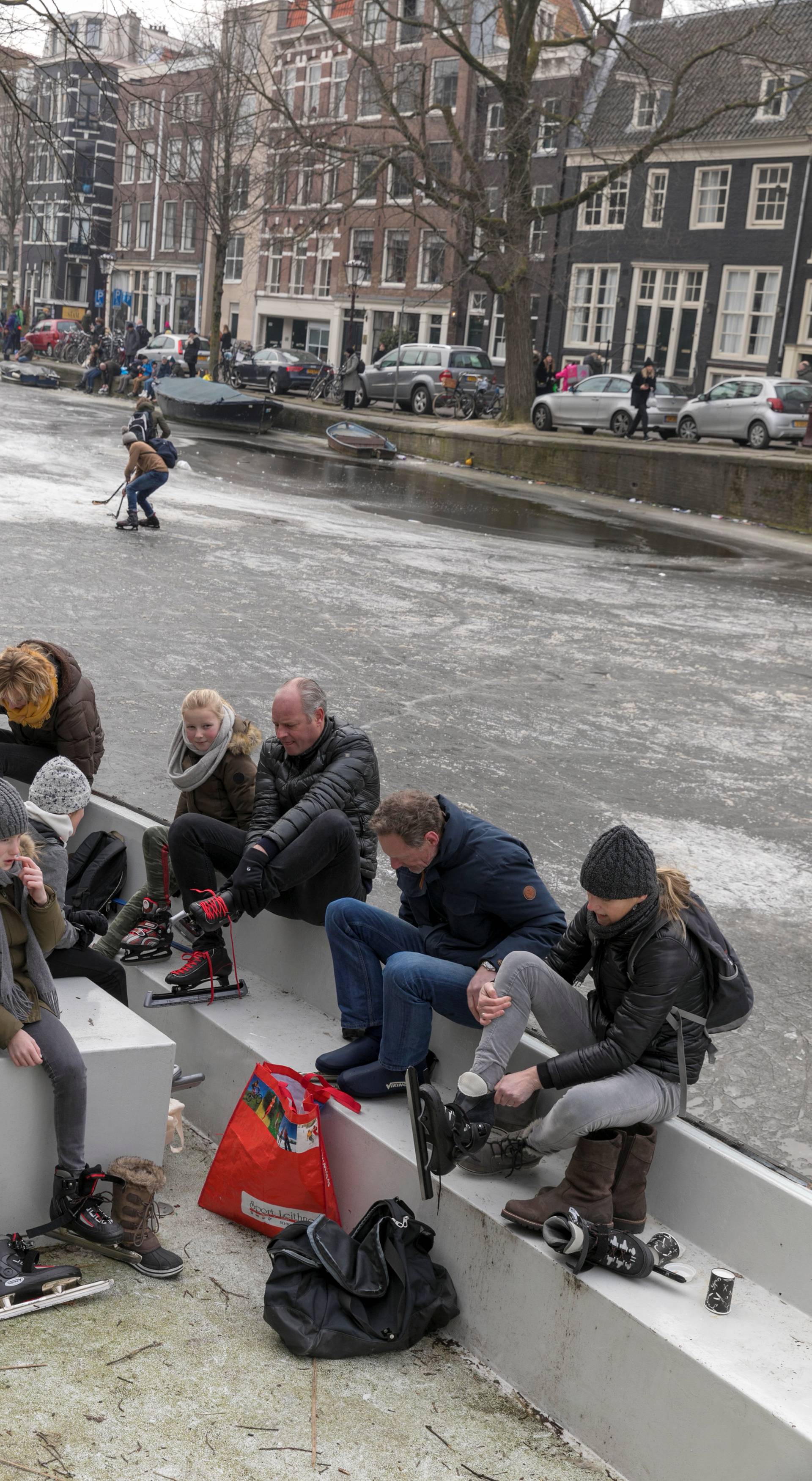 Ice skaters get ready to skate on frozen canal during icy weather in Amsterdam