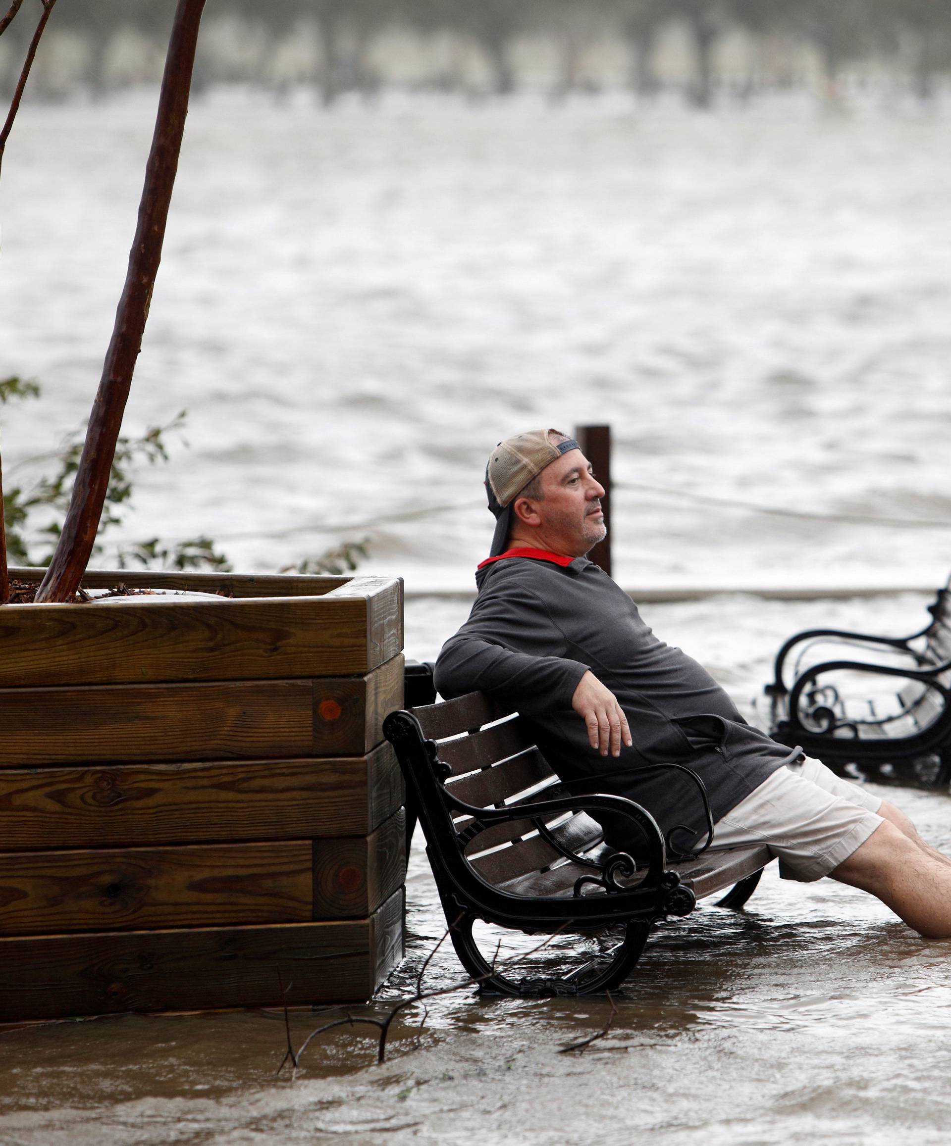 A man sits on a park bench in a flooded park as the Cape Fear River rises above its usual height in Wilmington, North Carolina