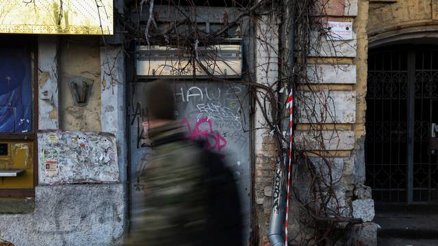 A man dressed in camouflage walks by graffiti painted wall in Kyiv