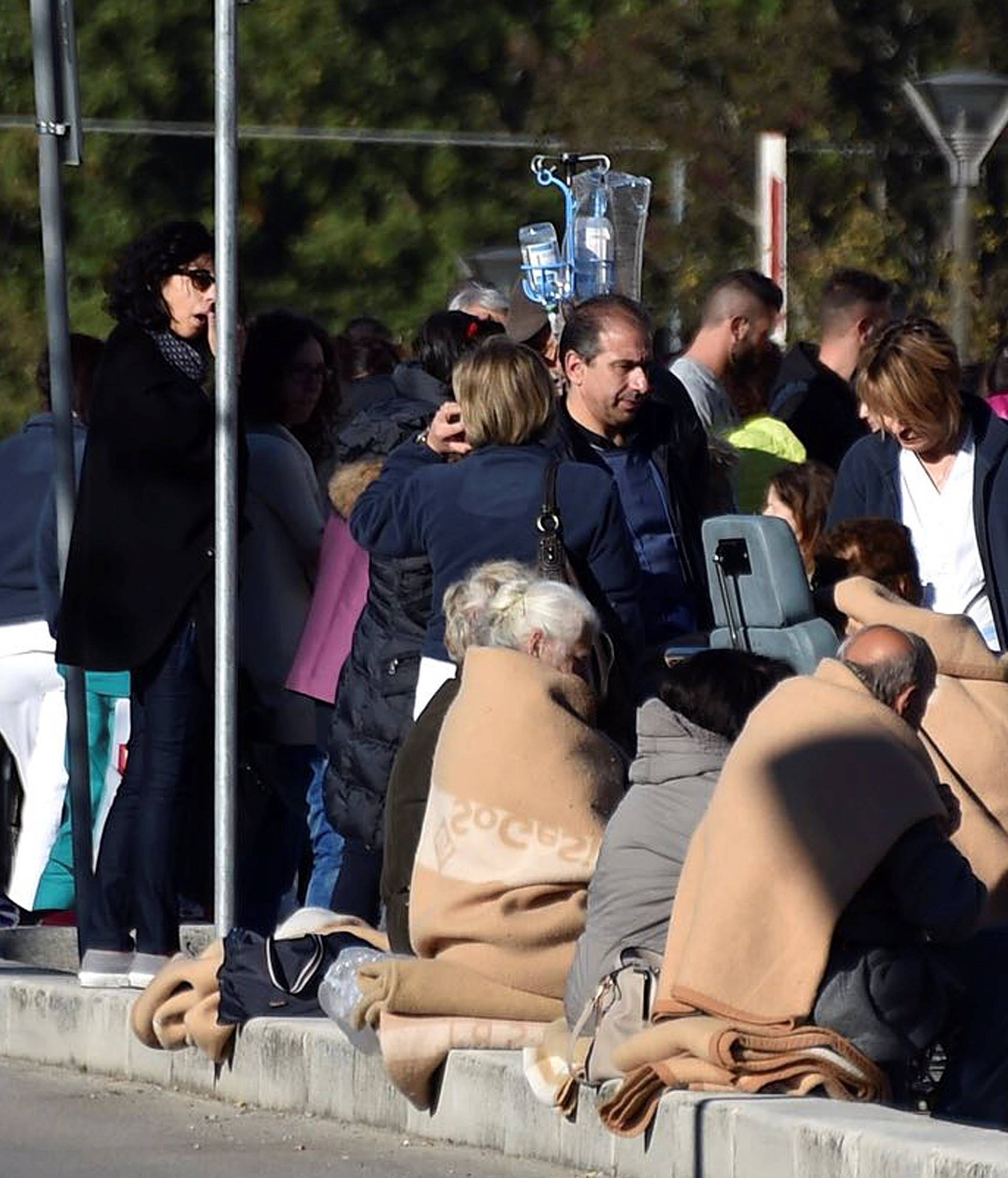People evacuated from an hospital are covered with blankets following a quake in Rieti