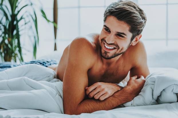 Happy attrective man relaxing at home in bed