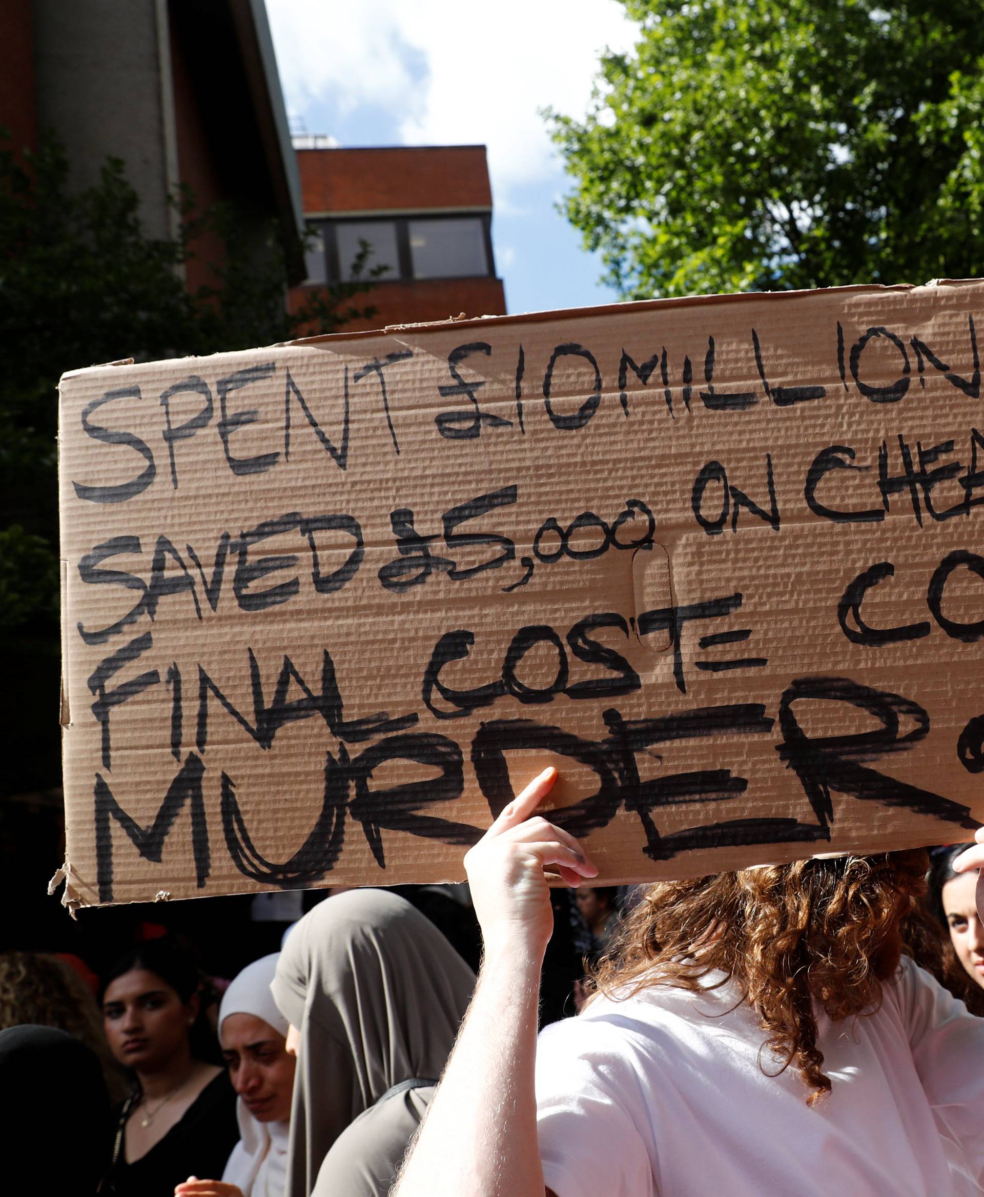 A demonstrator holds a banner during a protest at Kensington Town Hall, following the fire that destroyed The Grenfell Tower block, in north Kensington, West London