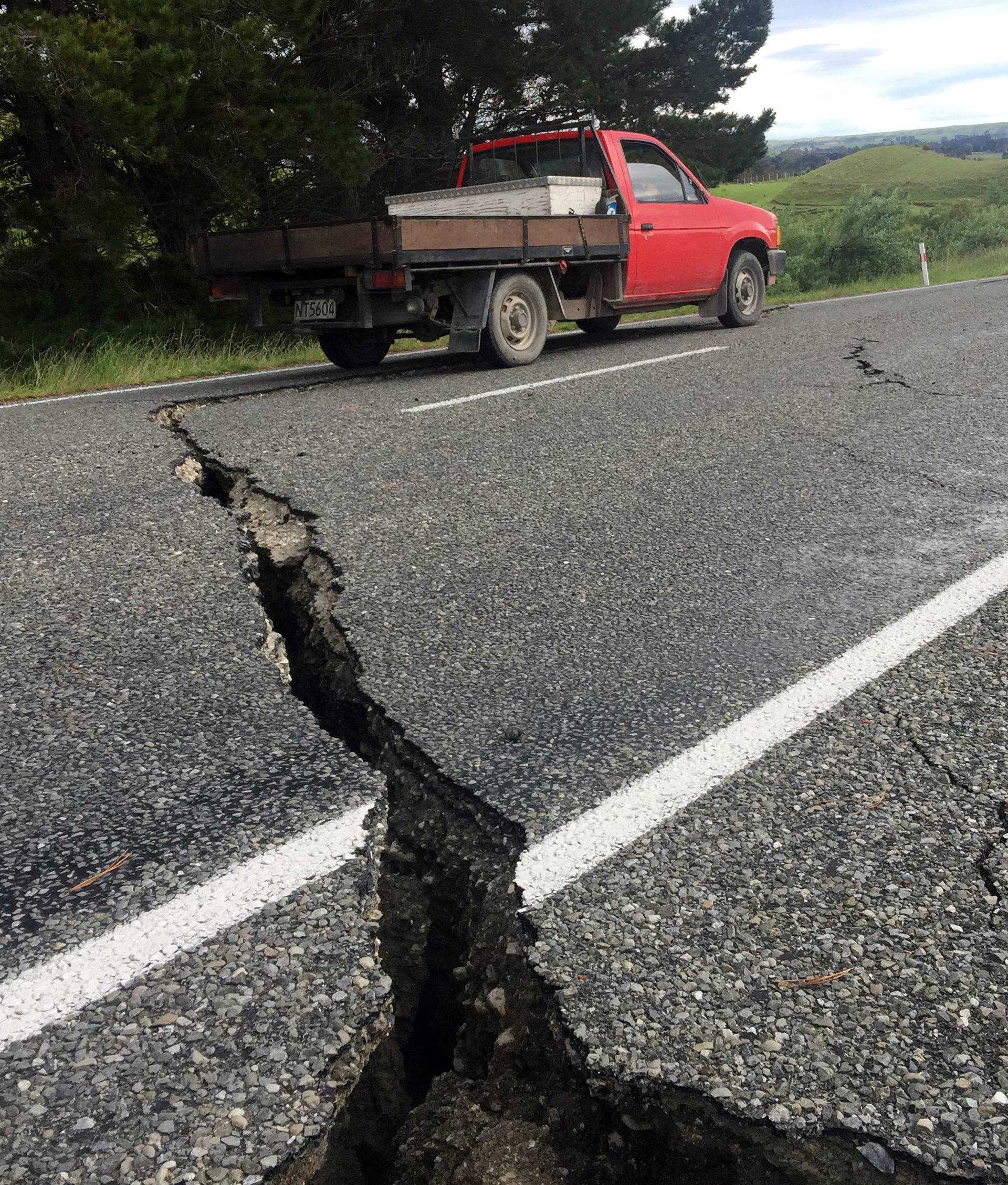 A truck drives over the fractured road caused by an earthquake south of the New Zealand town of Ward on the South Island